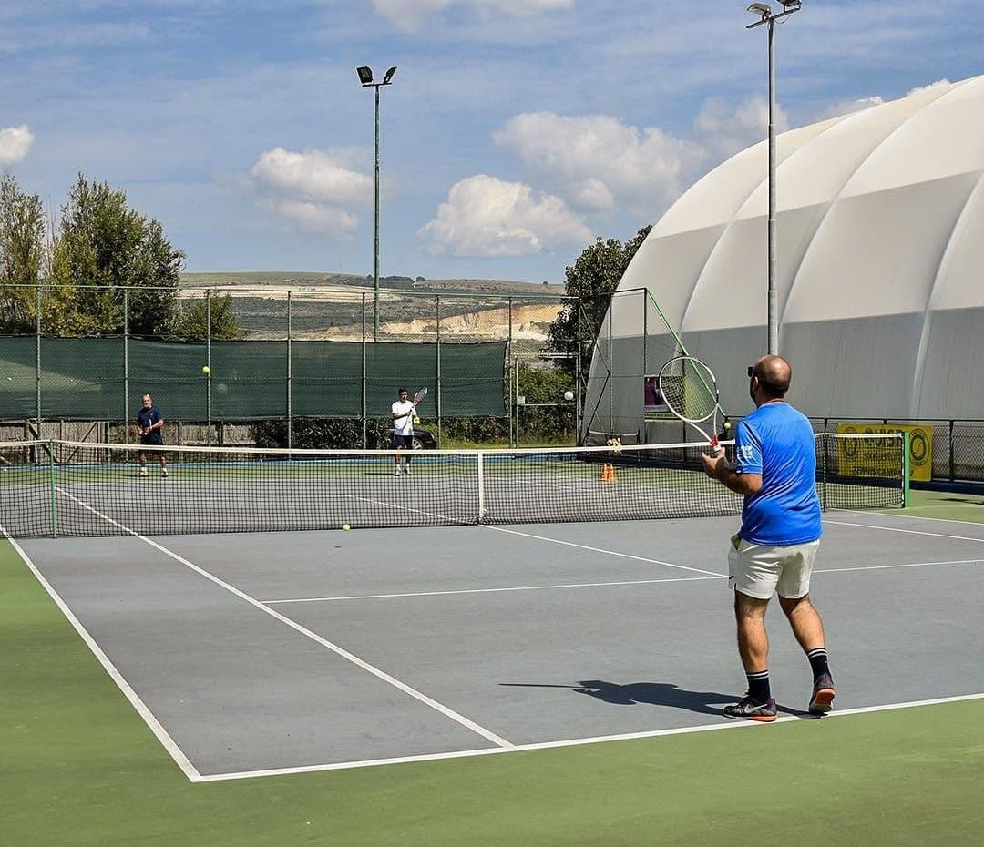 Partita sul campo all'aperto con le torri faro, la tensostruttura sullo sfondo e le colline