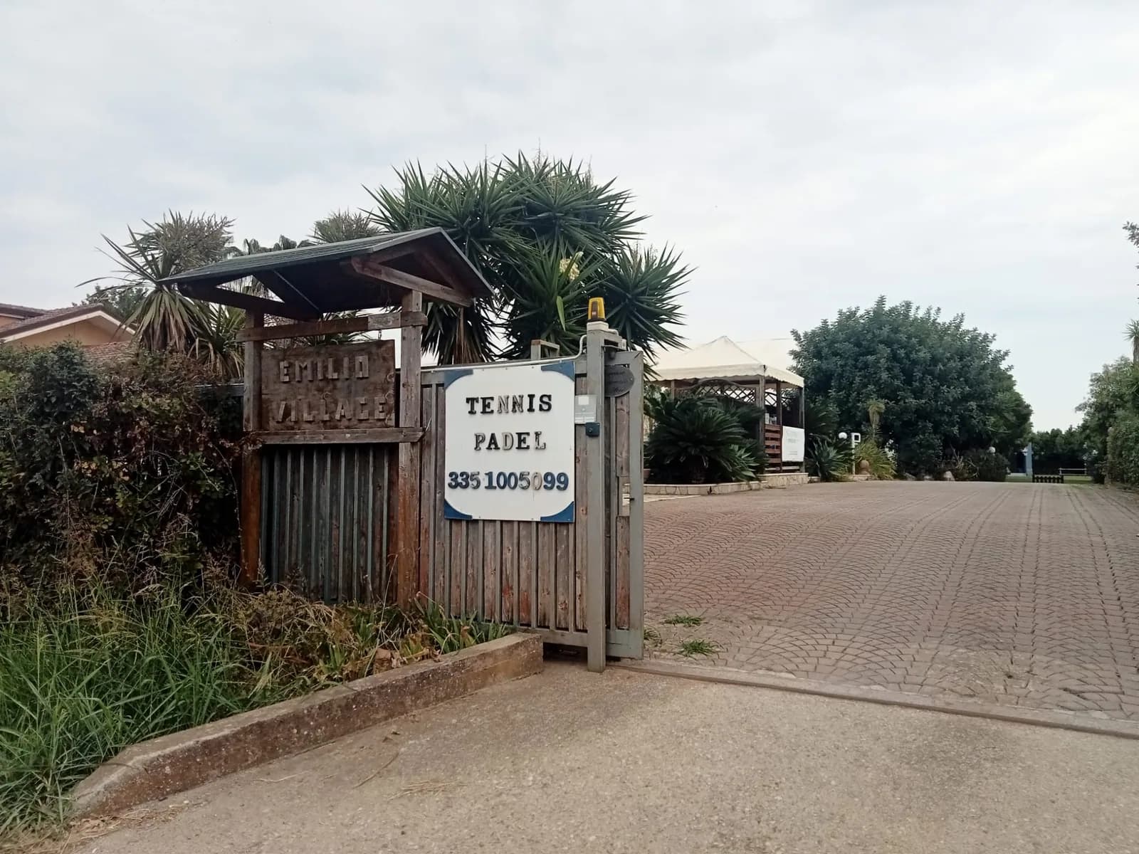 Ingresso dell'Emilio Village con cancello, insegna e viale alberato